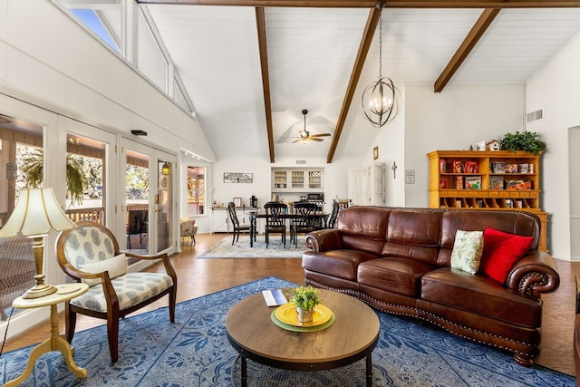 living room featuring hardwood / wood-style flooring, high vaulted ceiling, ceiling fan with notable chandelier, and beam ceiling