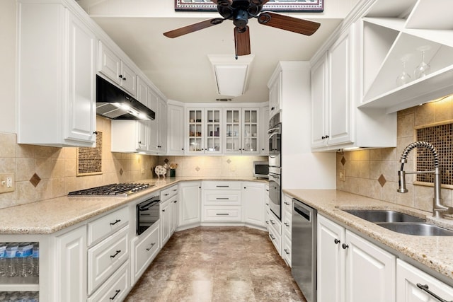 kitchen featuring sink, appliances with stainless steel finishes, white cabinetry, light stone counters, and decorative backsplash