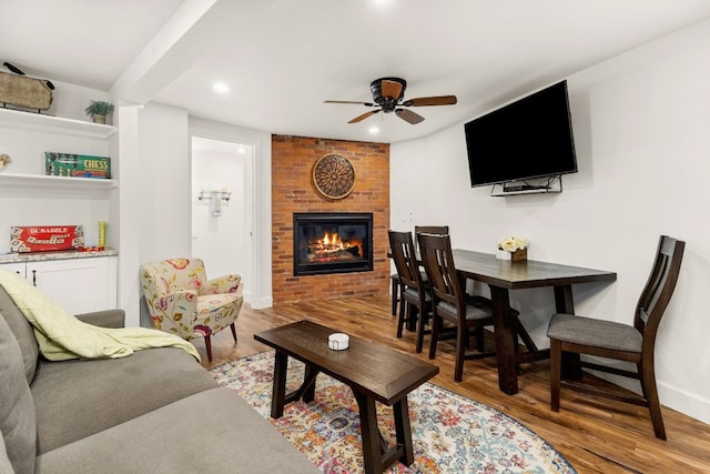 living room featuring a brick fireplace, ceiling fan, and light wood-type flooring