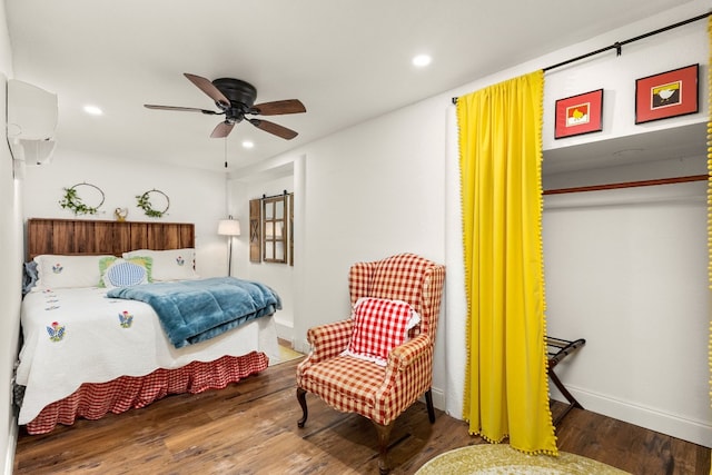 bedroom featuring ceiling fan, an AC wall unit, and dark hardwood / wood-style flooring