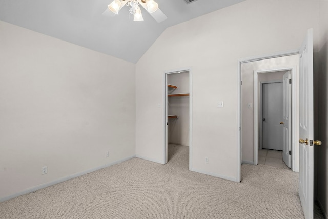 unfurnished bedroom with lofted ceiling, a spacious closet, light carpet, a closet, and ceiling fan