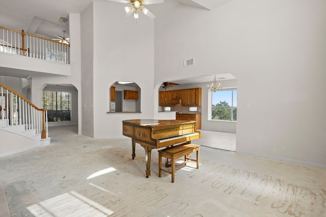 misc room featuring ceiling fan with notable chandelier and a high ceiling