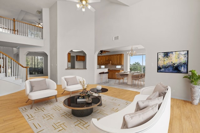 702 Timarron Dr, Leander, TX 78641 - living room featuring a ceiling fan, a high ceiling, light wood finished floors, a chandelier, and stairway