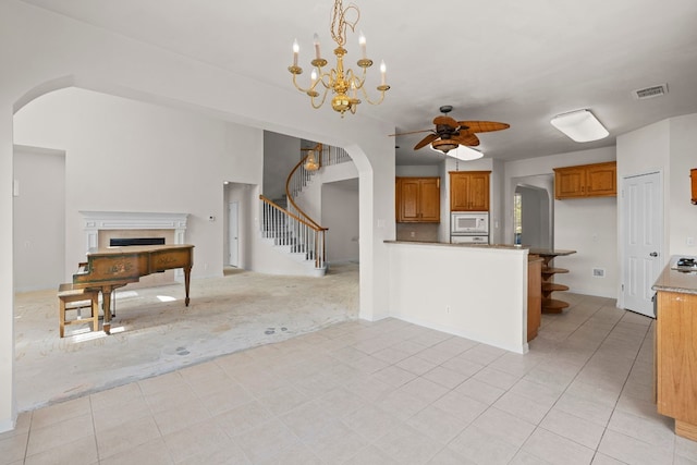 702 Timarron Dr, Leander, TX 78641 - kitchen featuring white microwave, open floor plan, arched walkways, a ceiling fan, and brown cabinets