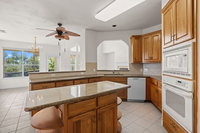 kitchen featuring sink, white appliances, light tile patterned floors, tasteful backsplash, and a kitchen island