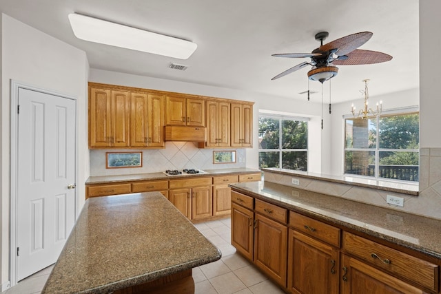 kitchen with pendant lighting, backsplash, a center island, light tile patterned floors, and white gas cooktop