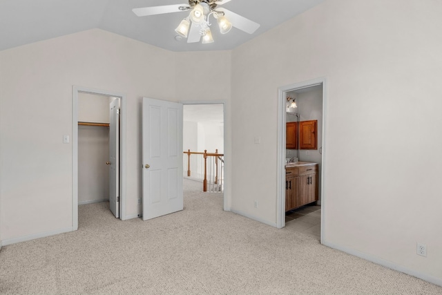 bedroom with vaulted ceiling, connected bathroom, sink, a walk in closet, and light carpet