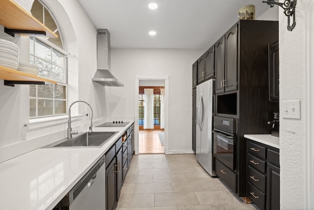 kitchen with light tile patterned flooring, black appliances, sink, and wall chimney range hood