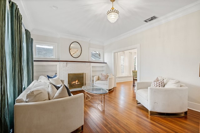 living room with crown molding, a brick fireplace, and hardwood / wood-style flooring