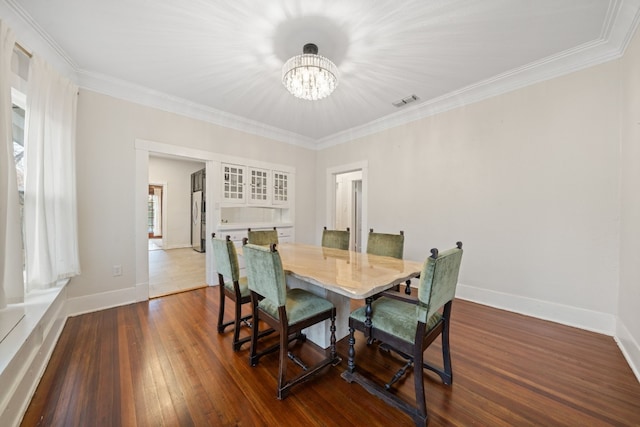 dining space with ornamental molding, dark hardwood / wood-style floors, and a chandelier