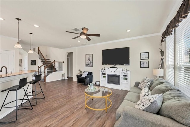 living room with sink, ornamental molding, dark hardwood / wood-style floors, and ceiling fan