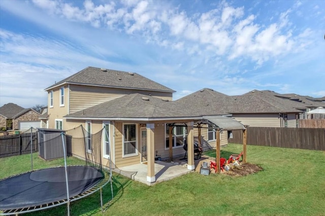 back of property with a trampoline, a yard, and a patio area