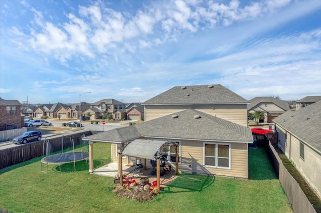 rear view of property featuring a patio, a trampoline, and a lawn