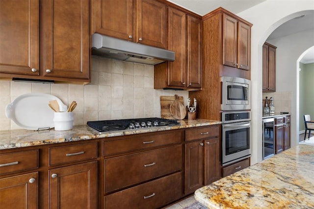 kitchen featuring light stone countertops, appliances with stainless steel finishes, wine cooler, and decorative backsplash