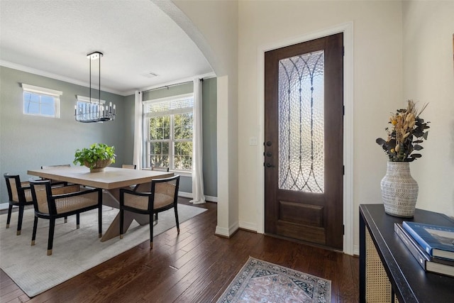 foyer featuring crown molding, dark hardwood / wood-style flooring, a chandelier, and a textured ceiling