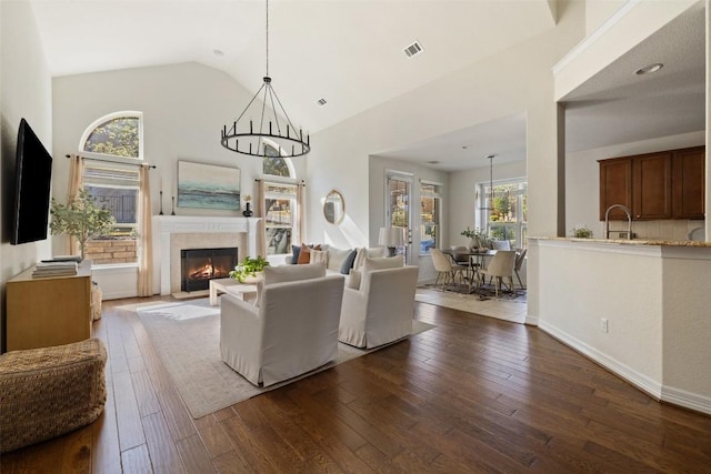 living room with wood-type flooring, high vaulted ceiling, sink, and a chandelier