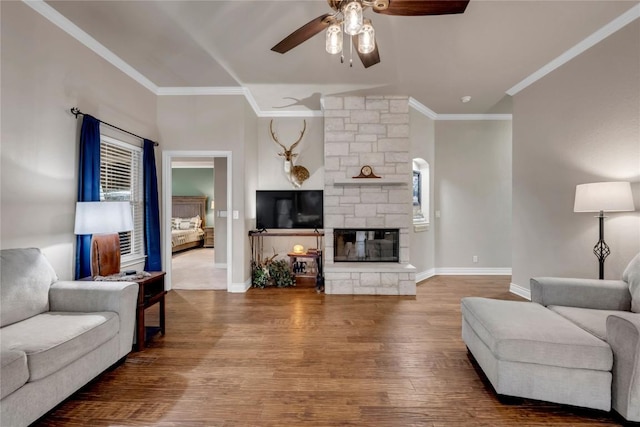 living room with ceiling fan, crown molding, a fireplace, and wood-type flooring