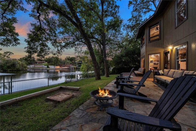 yard at dusk with a water view and an outdoor living space with a fire pit