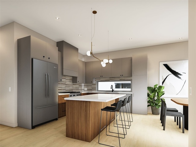 kitchen with a kitchen island, pendant lighting, sink, decorative backsplash, and wall chimney exhaust hood