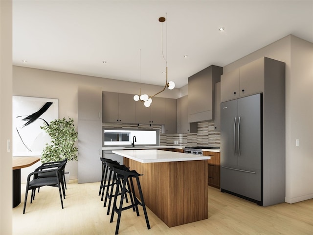 kitchen featuring sink, stainless steel refrigerator, a center island, decorative light fixtures, and wall chimney exhaust hood