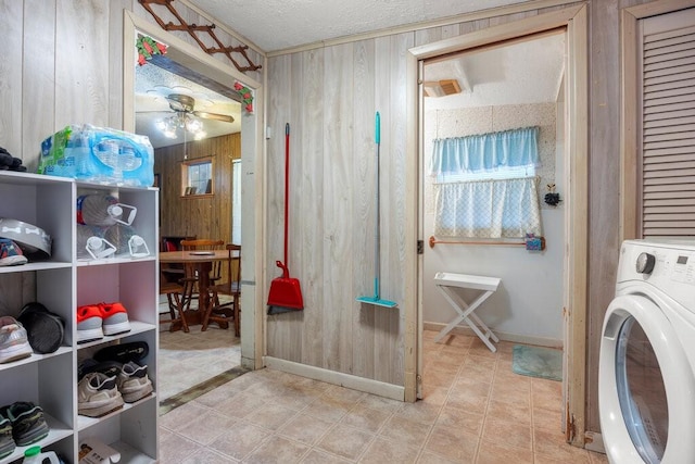 laundry room with ceiling fan, washer / dryer, a textured ceiling, and wood walls