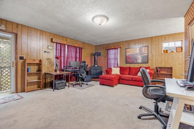 carpeted office space with a textured ceiling and a wood stove