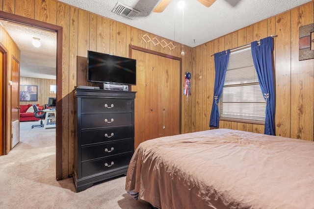 bedroom with ceiling fan, carpet floors, a textured ceiling, and wood walls