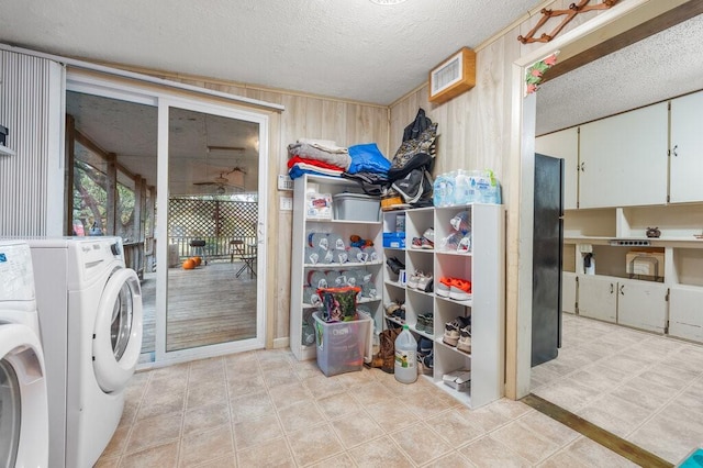 laundry room featuring washer / clothes dryer, wooden walls, and a textured ceiling