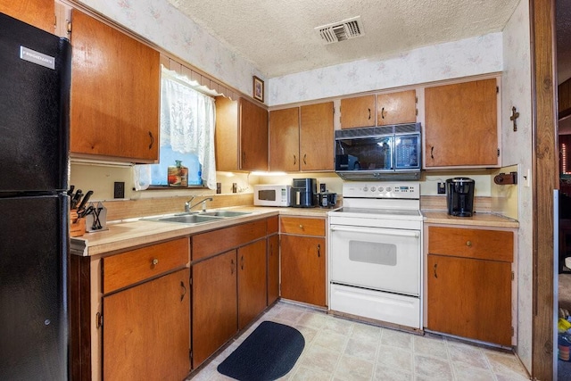 kitchen featuring sink, black appliances, and a textured ceiling