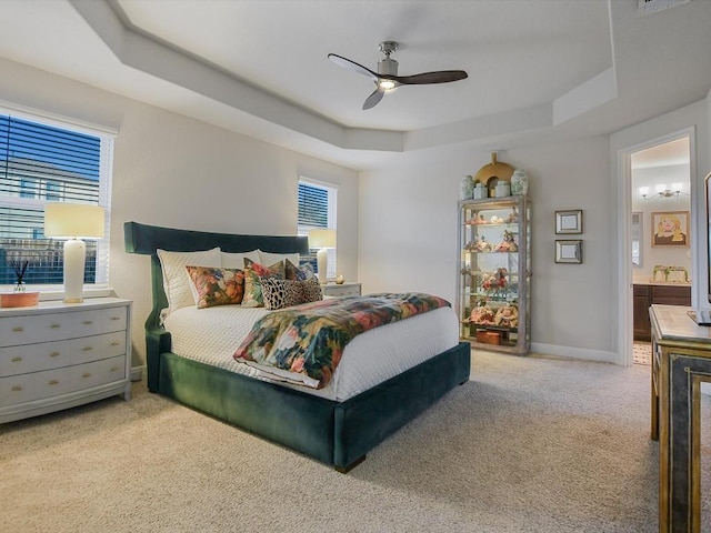 carpeted bedroom with a raised ceiling, multiple windows, and baseboards