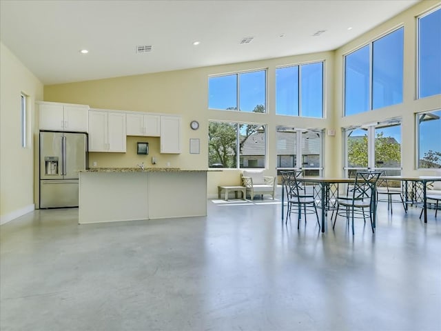 kitchen with white cabinetry, high end refrigerator, visible vents, and concrete flooring