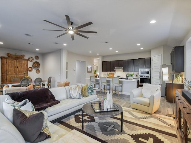 living room with light wood-style floors, visible vents, a ceiling fan, and recessed lighting