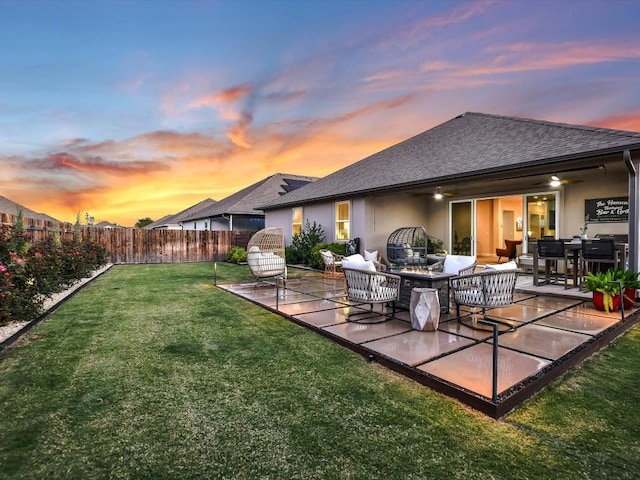 back house at dusk featuring ceiling fan, a yard, outdoor lounge area, and a patio area