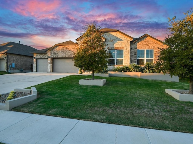 view of front of home with brick siding, concrete driveway, a lawn, an attached garage, and stone siding