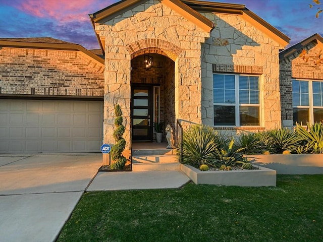 view of exterior entry featuring stone siding, concrete driveway, and an attached garage