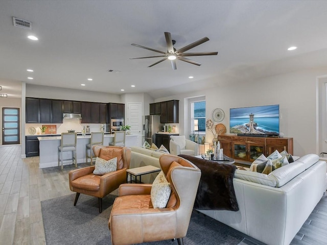 living room with light wood-type flooring, visible vents, and recessed lighting