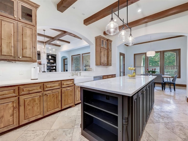 kitchen with pendant lighting, sink, beam ceiling, and a kitchen island