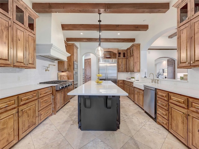 kitchen with pendant lighting, built in appliances, custom range hood, a kitchen island, and decorative backsplash