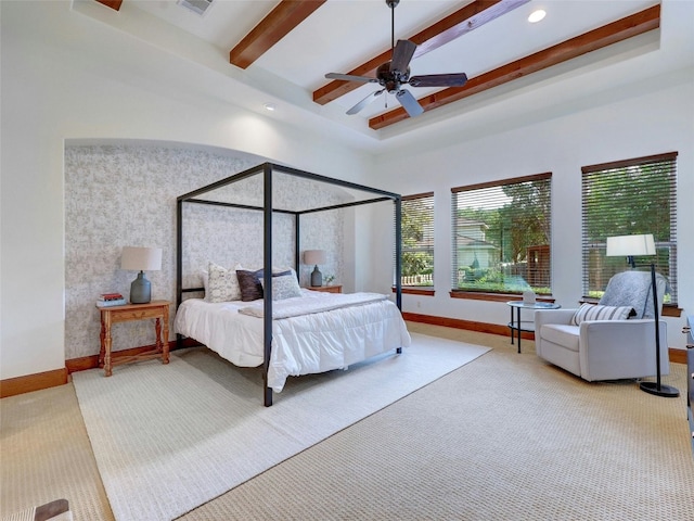 carpeted bedroom with beamed ceiling, a raised ceiling, and ceiling fan