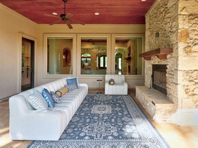 living room featuring ceiling fan, a stone fireplace, and wood ceiling