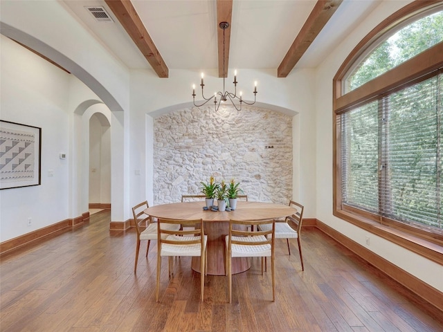 dining space featuring an inviting chandelier, hardwood / wood-style flooring, and beamed ceiling