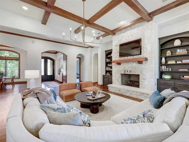 living room featuring beamed ceiling, built in features, a notable chandelier, and dark hardwood / wood-style flooring