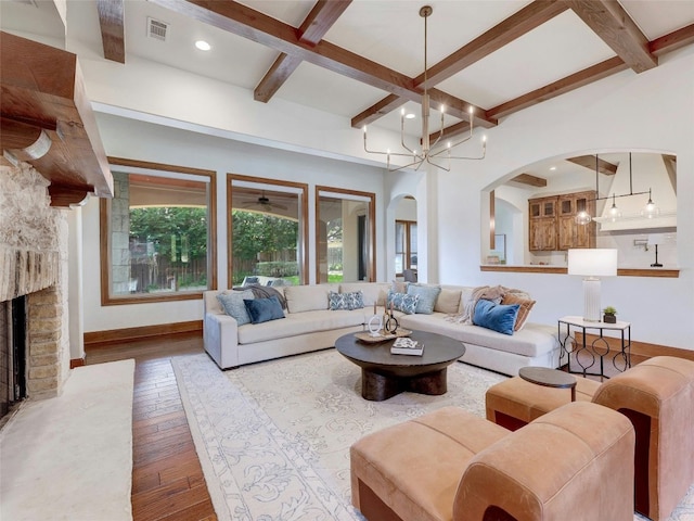 living room with beam ceiling, a brick fireplace, coffered ceiling, and light wood-type flooring