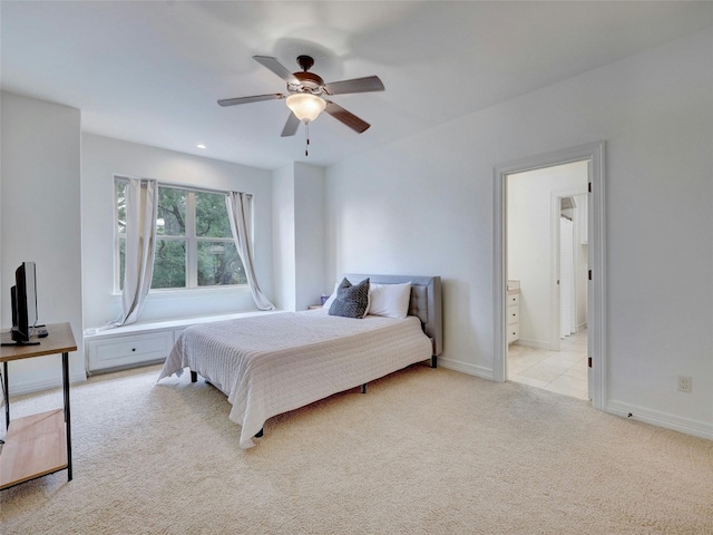 bedroom with ceiling fan, light colored carpet, and ensuite bathroom