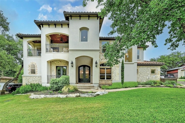 mediterranean / spanish-style home with french doors, a balcony, and a front yard