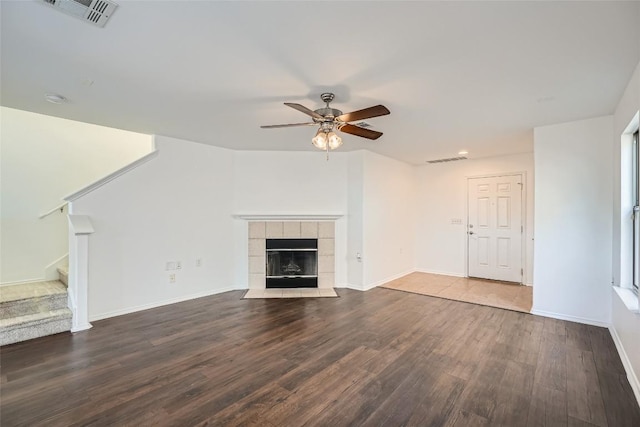 unfurnished living room with dark wood-type flooring, ceiling fan, and a tile fireplace