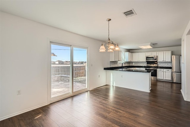 kitchen featuring white cabinetry, decorative backsplash, hanging light fixtures, kitchen peninsula, and stainless steel appliances