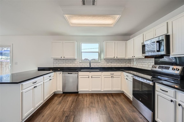 kitchen with sink, white cabinetry, stainless steel appliances, a healthy amount of sunlight, and kitchen peninsula