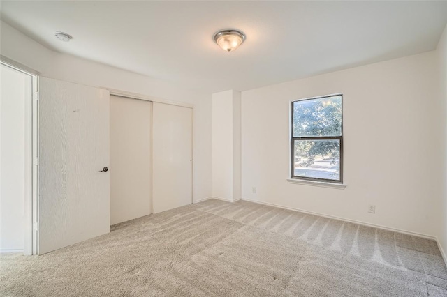 unfurnished bedroom featuring light colored carpet and a closet