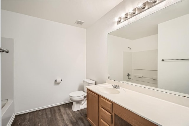 full bathroom with hardwood / wood-style flooring, vanity, washtub / shower combination, and toilet